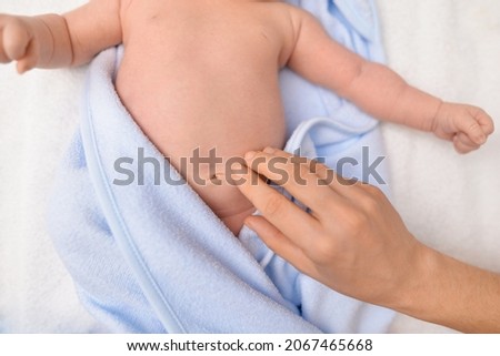 Treatment of newborn baby navel. Mother's hand and newborn's navel. First days after birth. Daily grooming. Care about baby clean and soft body skin. Closeup. Healthy stomach, a cure for gas. Royalty-Free Stock Photo #2067465668