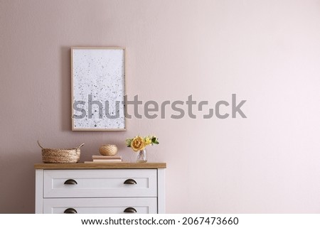 Beautiful bouquet, books and decor on chest of drawers near beige wall indoors, space for text. Interior design