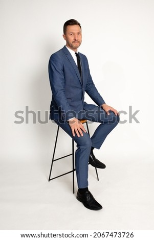 Full length portrait of man in suit sitting on chair, isolated on white background. Copy space Royalty-Free Stock Photo #2067473726
