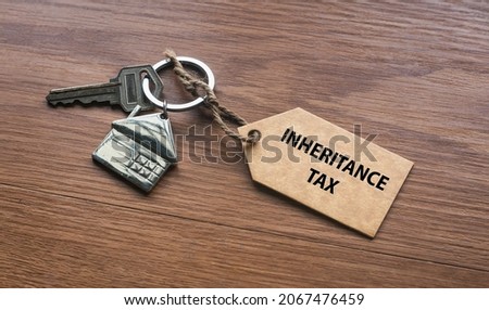 A house key with a tag written with Inheritance Tax on wooden background. Royalty-Free Stock Photo #2067476459