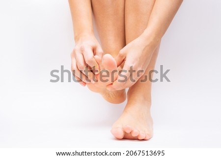 Pain in the foot and toes from uncomfortable shoes. A woman holds a sore foot with her hands on a white background. Pathology of bone structures, flat feet. Cramp, convulsion, spasm. Orthodontics Royalty-Free Stock Photo #2067513695