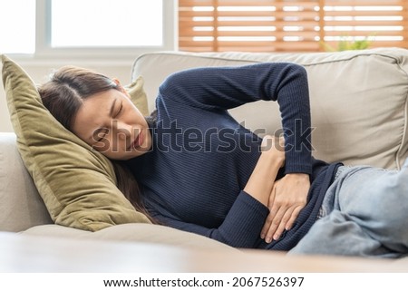 Flatulence asian young woman, girl hand in stomach ache, suffer from food poisoning, abdominal pain and colon problem, gastritis or diarrhoea. Patient belly, abdomen or inflammation, concept. Royalty-Free Stock Photo #2067526397