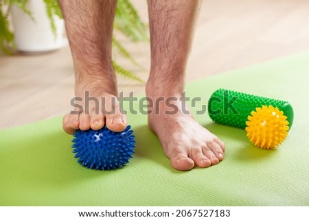 man doing flatfoot correction gymnastic exercise using massage ball at home