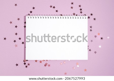 Notepad with mockup on purple star shape glitter on violet background. Flat lay style for holiday, birthday, wedding, new year, christmas, party, celebration concept