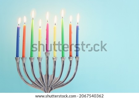 Image of jewish holiday Hanukkah with menorah (traditional candelabra) and candles over pastel blue background