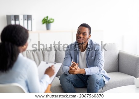 Effective psychotherapy. Young black guy talking to his psychologist, receiving professional help at mental health clinic. African American male patient sharing therapy results with counselor Royalty-Free Stock Photo #2067560870