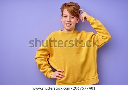 Portrait of pensive teen boy isolated on purple background. Thoughtful teenager holding hand on head, looking at camera. Beautiful caucasian funny child in shirt is thinking, in contemplation Royalty-Free Stock Photo #2067577481