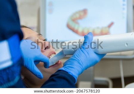 Great concept of dental procedure, young blond Brazilian woman in the dental chair suffering dental procedure by dentist as use of visualization monitor and image enlargement of the tooth.