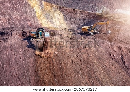 Excavators are digging to hill to make a road. Excavators are heavy construction equipment consisting of a boom, dipper (or stick), bucket and cab on a rotating platform.