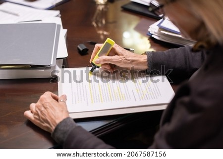 Hands of contemporary female lawyer with yellow highlighter underlining the main terms of contract or other juridical document Royalty-Free Stock Photo #2067587156