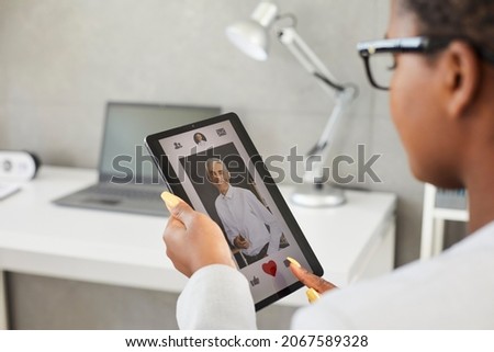 Dating online application. Lonely woman uses digital tablet to find love. Young African American woman on dating site or in application presses red heart as sign of sympathy for handsome Caucasian man