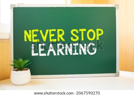 Never Stop Learning in chalk on the school board, Search engine optimization and websites. Desk, swept balls of paper, computer keyboard