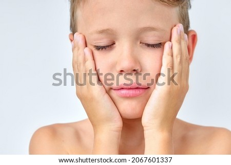 Calm sleepy boy touching cheeks, keeping eyes closed, isolated on white studio background, want to sleep in the morning after wake up. little shirtless boy need more rest