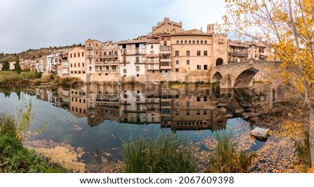 Valderrobres old town reflected on the river at autmn, Roman bridge over the river. Valderrobres, Matarraña, Teruel, Aragon, Spain. Panoramic picture.