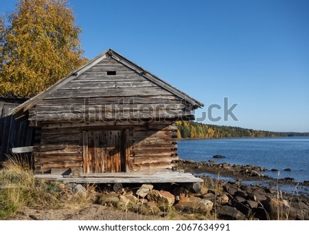 A very old weathered wood barn on the shores of the white sea in autumn. Russian North