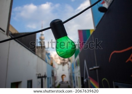 green lamp bulb in front of an urban art street 