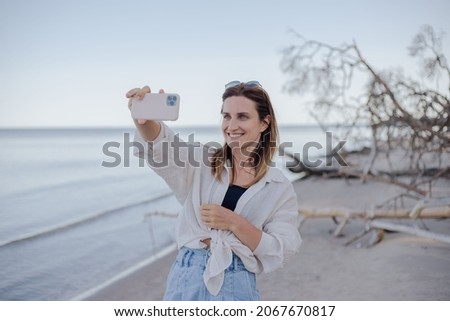 Photo of cute young emotional caucasian woman make selfie by camera on the beach.