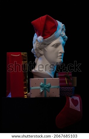 Design for postcards for Christmas and New Year. White plaster sculpture of a bust of Apollo in a red cap of Santa Claus