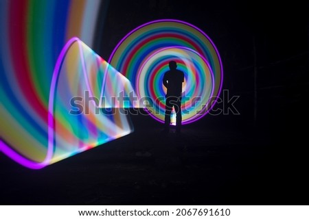 one person standing against beautiful rainbows circle light painting as the backdrop