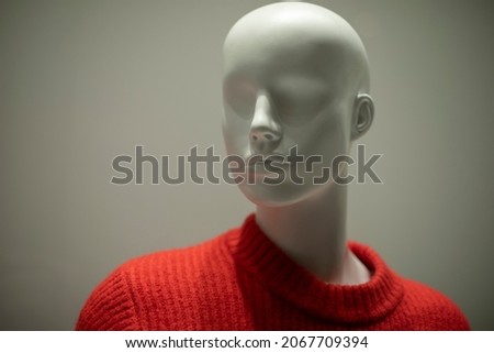 Mannequin in a red sweater. Shop window. Wool-bound clothing. Women's mannequin without hair.