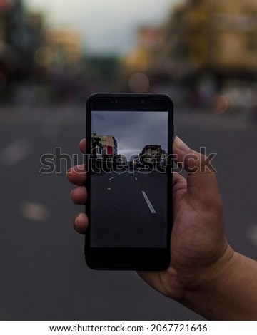 A closeup shot of a person taking a photo of a street