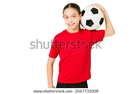 Beautiful little girl arriving to her soccer lessons. Preteen girl smiling and looking at the camera while holding a ball