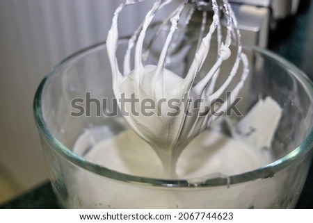 View of a mixer whisk with stiff consistency royal icing. Making royal icing to decorate sugar cookies. Royalty-Free Stock Photo #2067744623