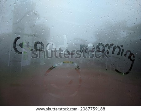 Rain drops on car windshield Good morning text written on it with a laughing smiley.windshield on a rainy day.writing on wet glass stock images.Good morning text on wet glass texture download.