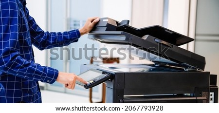 Businessmen press button on the panel for using photocopier or printer for printout and scanning document paper at office. Royalty-Free Stock Photo #2067793928