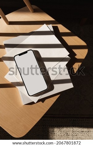 Flatlay of blank clipping path screen mobile phone with sunlight shadows. Aesthetic home office desk workspace. Lady, girl boss business, work, blog template with mockup space. Flat lay, top view