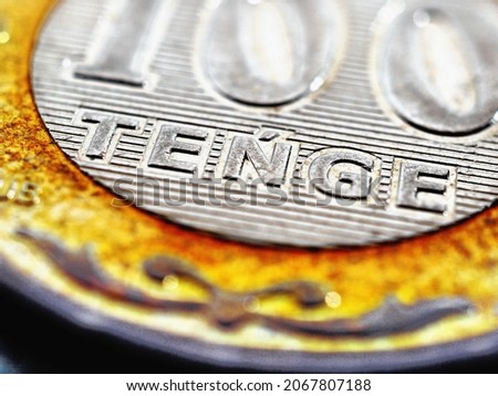 Translation of the inscription: tenge. Fragment of a Kazakh coin in 100 tenge. The name of the national currency in close-up in Latin. Economy, business and finance in Kazakhstan