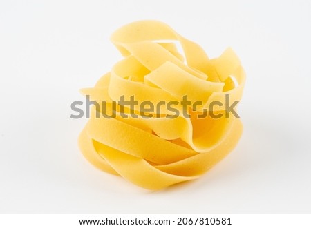 pasta yellow isolated on white background. Homemade egg pasta tagliatelle. Raw nest noodles, uncooked ribbon fettuccine, dry long rolled macaroni isolated on white background top view Royalty-Free Stock Photo #2067810581
