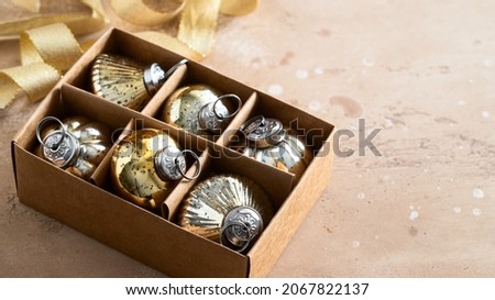 Different shape vintage Christmas balls into the box on  beige background with ribbon. Merry Christmas concept.