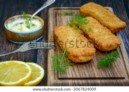 Close up of   Crispy breaded  deep fried fish fingers with breadcrumbs served  with remoulade sauce and  lemon Cod Fish Nuggets on rustic wood table background