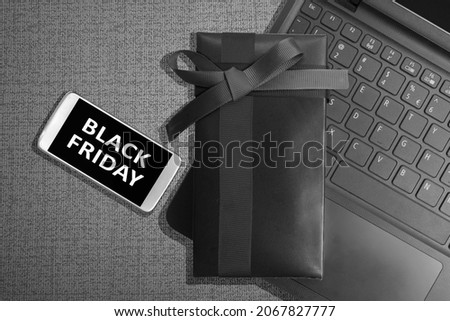 Black Friday message on the mobile phone screen with gift box on black background. Black Friday concept