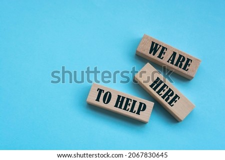 Above are three wooden blocks with the words WE ARE HERE TO HELP.
