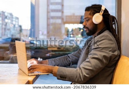 Hispanic business man drinking coffee and listening to music with poratil in a coffee shop at night