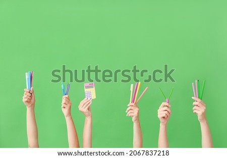 Many different hands with school supplies on green background