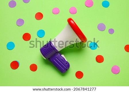 Toy megaphone and paper circles on color background