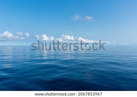 Beautiful blue sky, with fluffy clouds over the calm Pacific Ocean. 