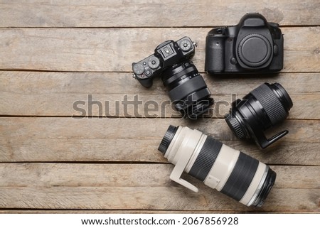 Digital cameras and lenses on wooden background