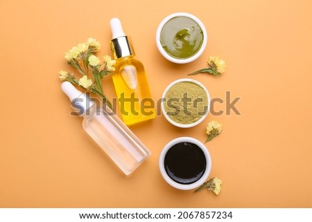Henna in bowls and bottles of essential oil on color background