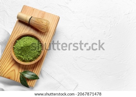 Bowl with powdered matcha tea and chasen on light background