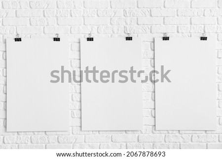 Blank posters hanging on white brick wall