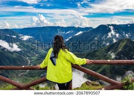 isolated young girl watching mountain valley filled with low cloud and dramatic sky at morning image is taken at latilum peak shillong meghalaya india. Royalty-Free Stock Photo #2067890507