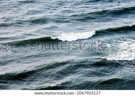 Deep blue sea waters splashing with foamy waves. Aerial view of ocean splashing waves, dark blue wavy sea waters with white foam. Water surface, natural background, copy space