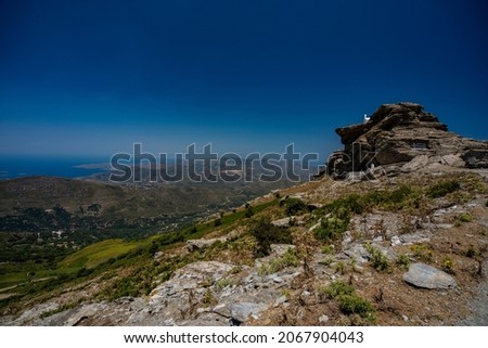 greece hike ,white church with greek flag on top of the Highest rock on top of Andros island, panorama over the Island and ocean , Batsi
