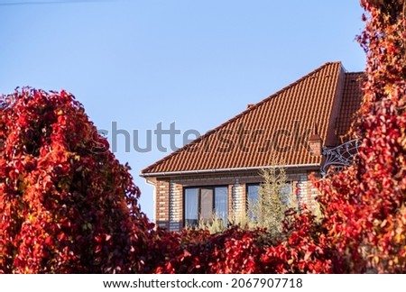 The roof is made of red metal tiles in the fall. Royalty-Free Stock Photo #2067907718