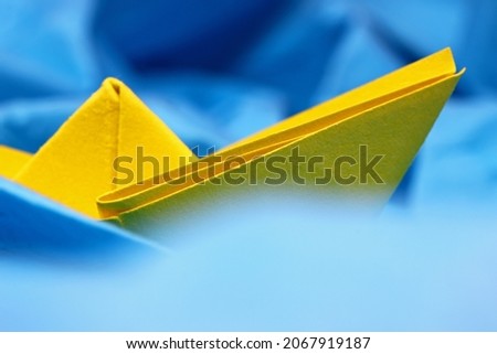 Yellow paper boat on blue paper. Sea ​​voyage concept
