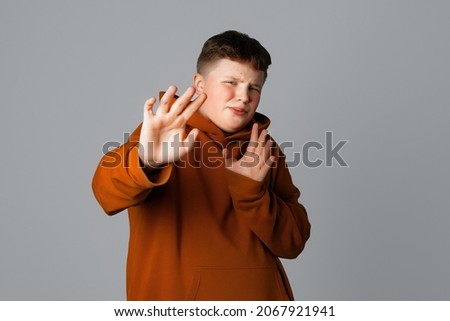 Stay away, keep social distance. Reluctant and displeased plus size teenager boy show block, stop gesture, say no, refusing something, step back from someone, standing against gray background Royalty-Free Stock Photo #2067921941